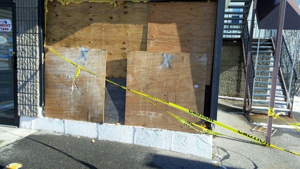 storefront wall boarded up after a collision